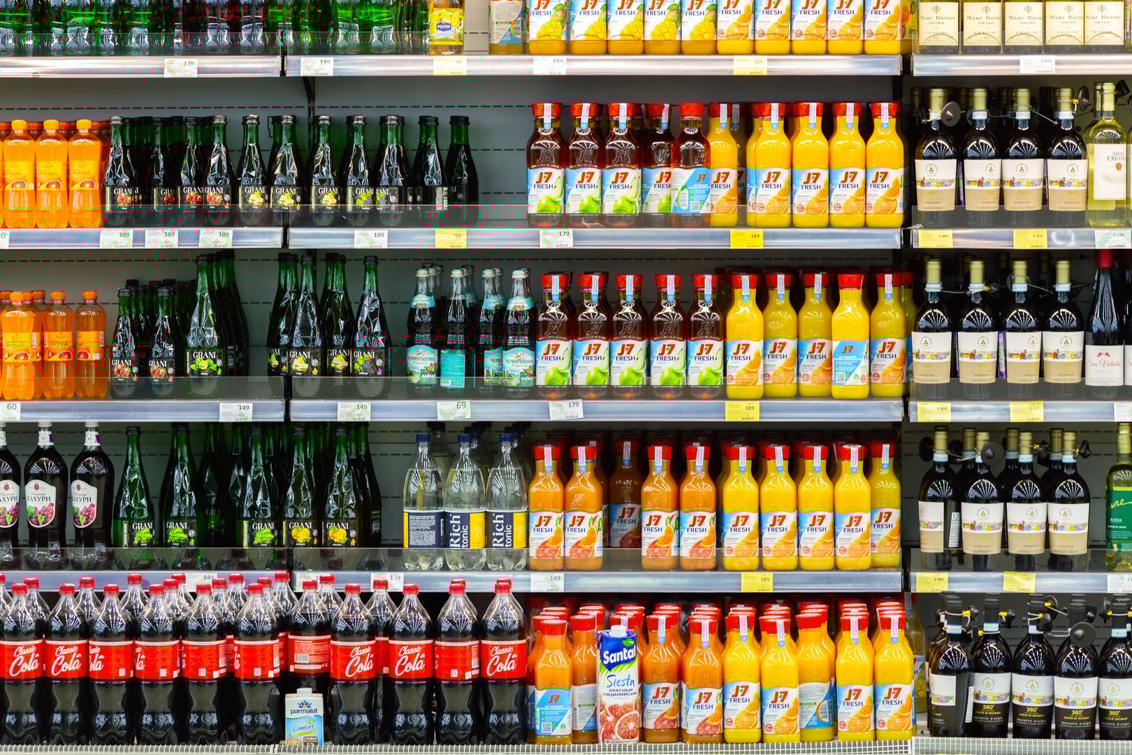 Moscow, Russia - December 29, 2024: Supermarket shelves with various packs and bottles of fruit juice J7, Coca-Cola, Rich and wine. Retail industry. Grocery shopping