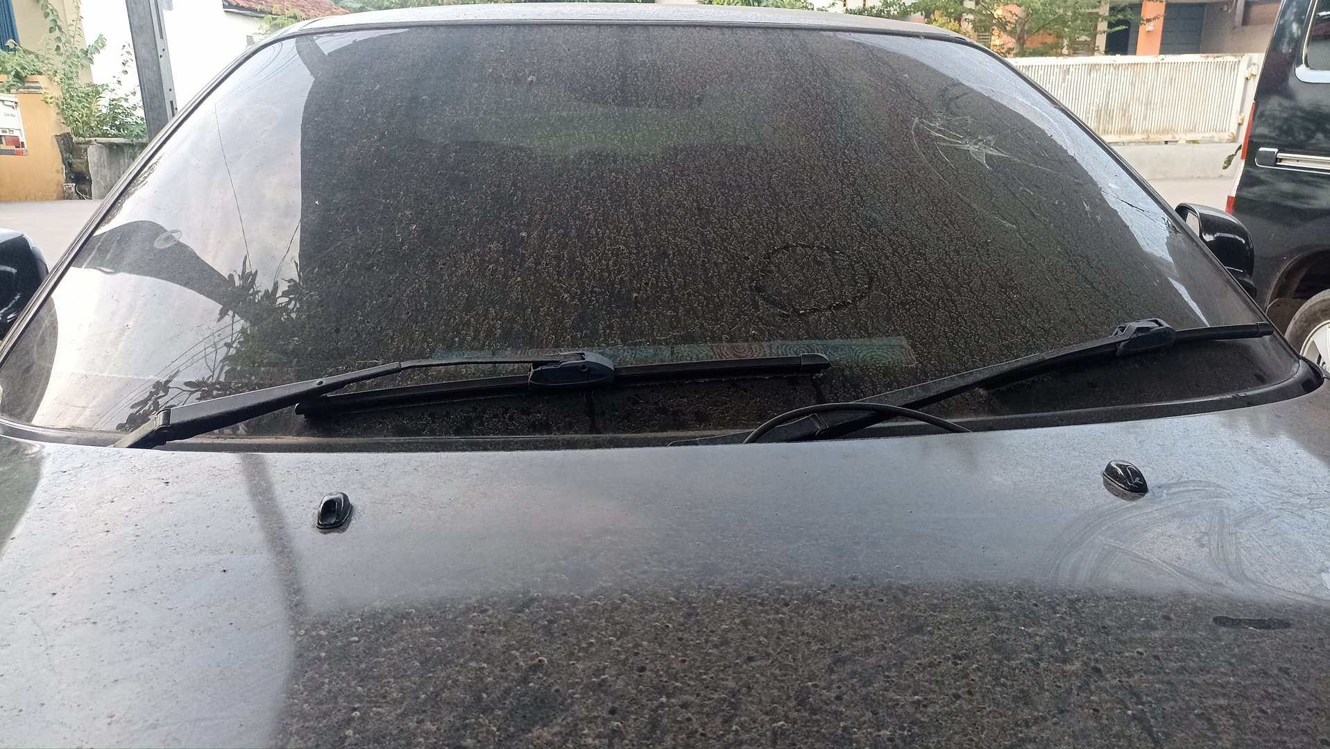 Close up of wiper and dirty car window full of dust.