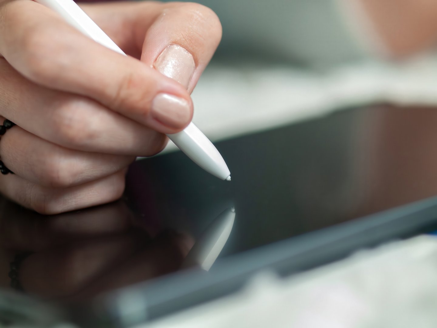 This is a closeup image of a hand gracefully using a stylus on a tablet, which is perfect for digital design and art