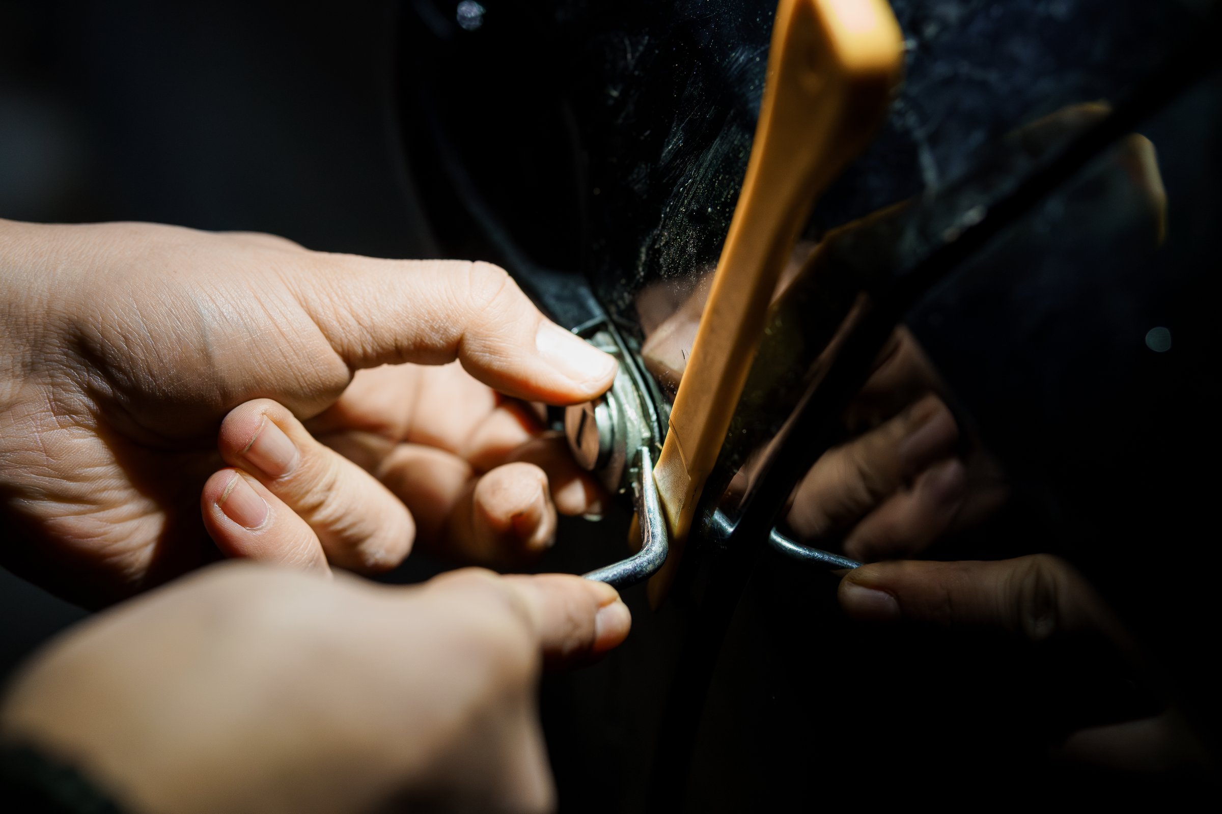 A Close-Up of Hands Picking a Lock with a Slim Jim Tool at Night.