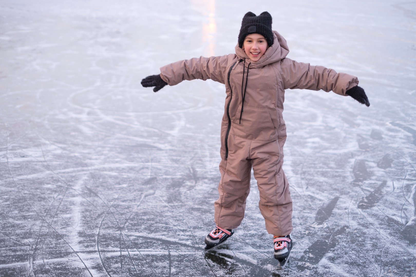 A child learns to ride canyons on the ice rink of a frozen lake while keeping his balance.