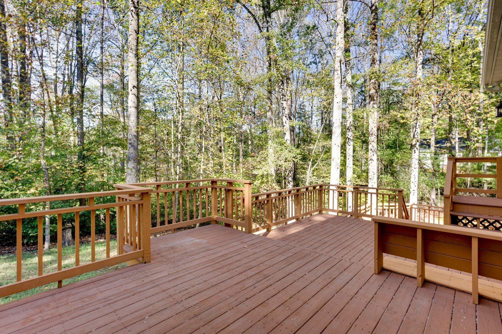A large wooden deck provides an expansive view of a lush forest, creating a serene and natural atmosphere, perfect for relaxation and outdoor gatherings.