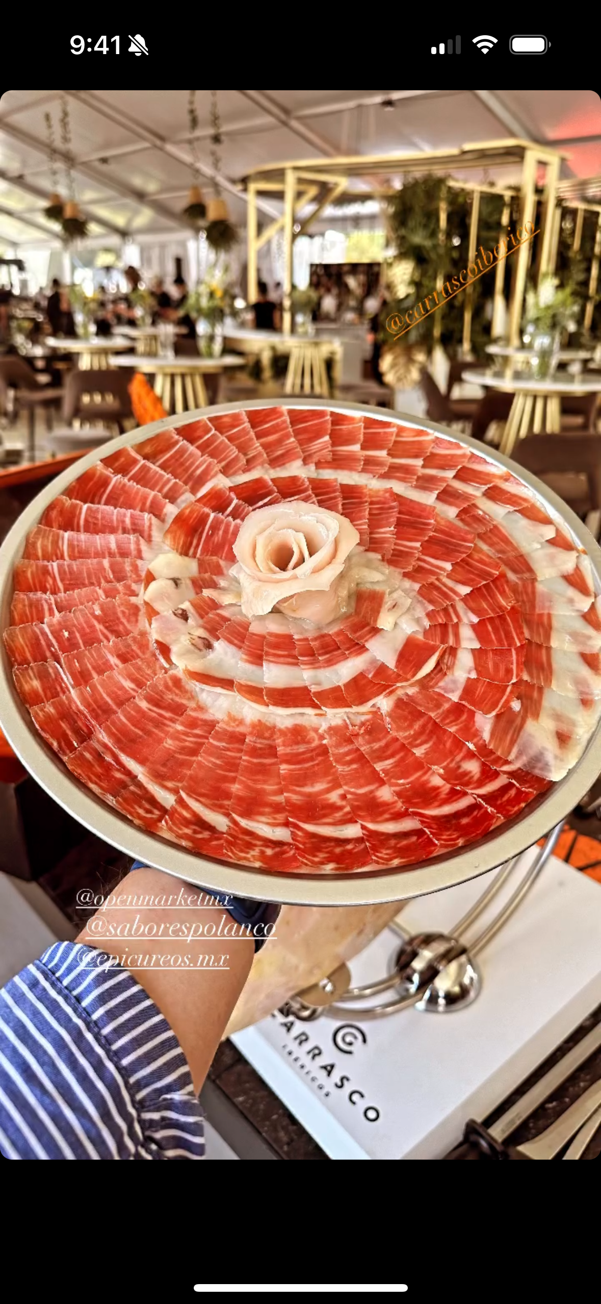 A platter of thinly sliced cured ham arranged in a circular pattern with a rose-shaped ham centerpiece.