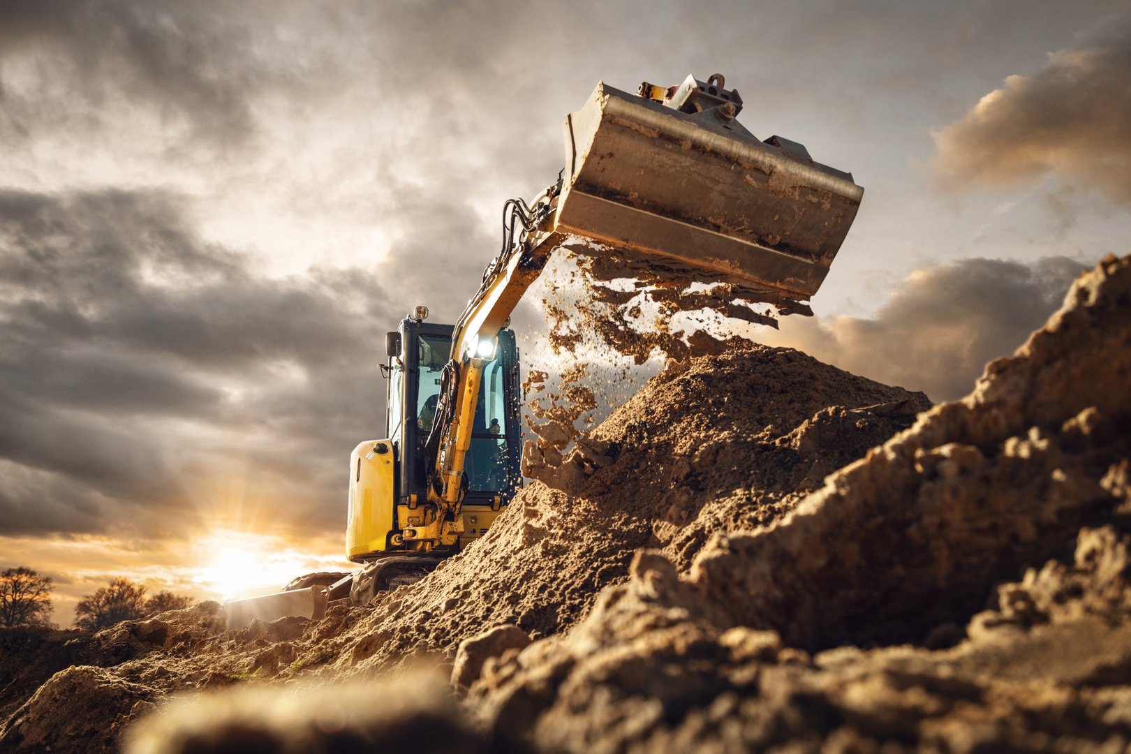 An excavator at work on a large dirt pile, with a dramatic sky. The artwork captures the power and fascination of construction machinery.