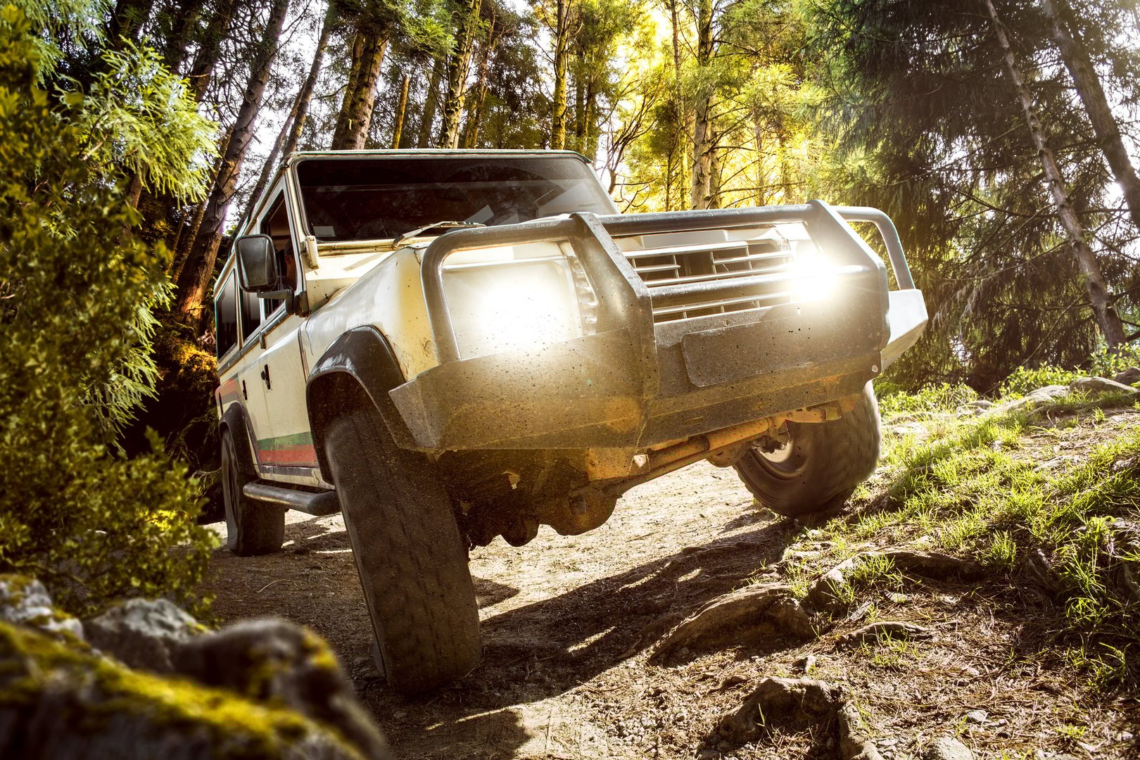 Vintage off-road car driving on rough terrain in the forest.