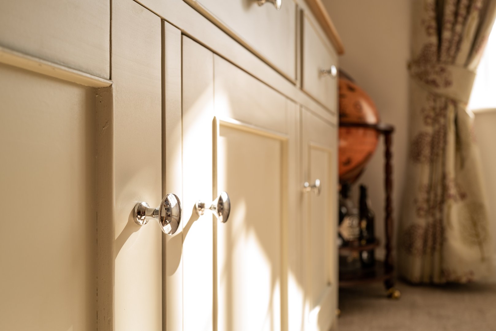 Abstract view of a wooden cupboard seen in a luxury villa. A nearby drinks globe can be seen.