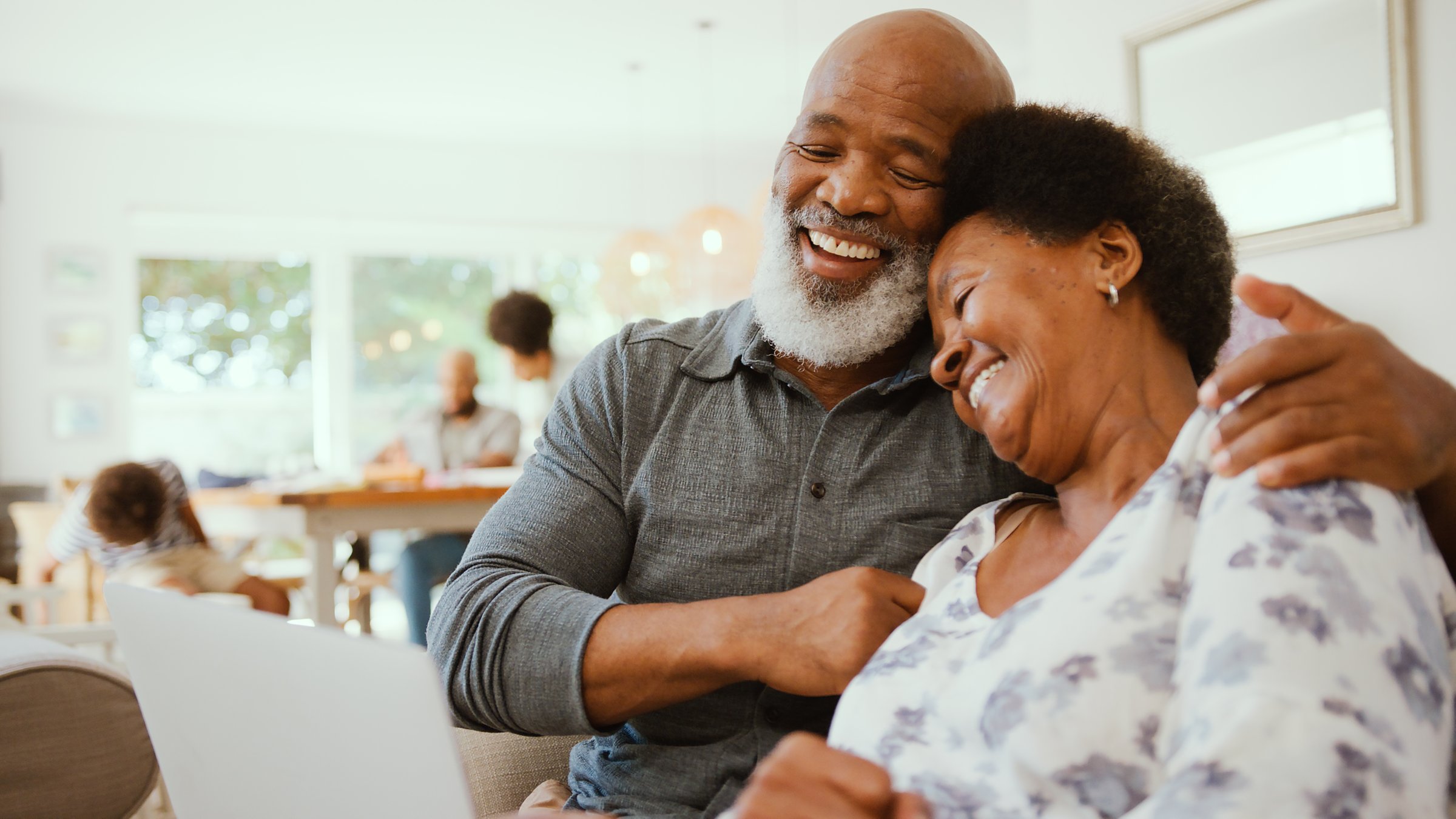 Couple de retraités souriants à La Réunion utilisant un ordinateur pour simuler leur rachat de crédit avec pension stable
