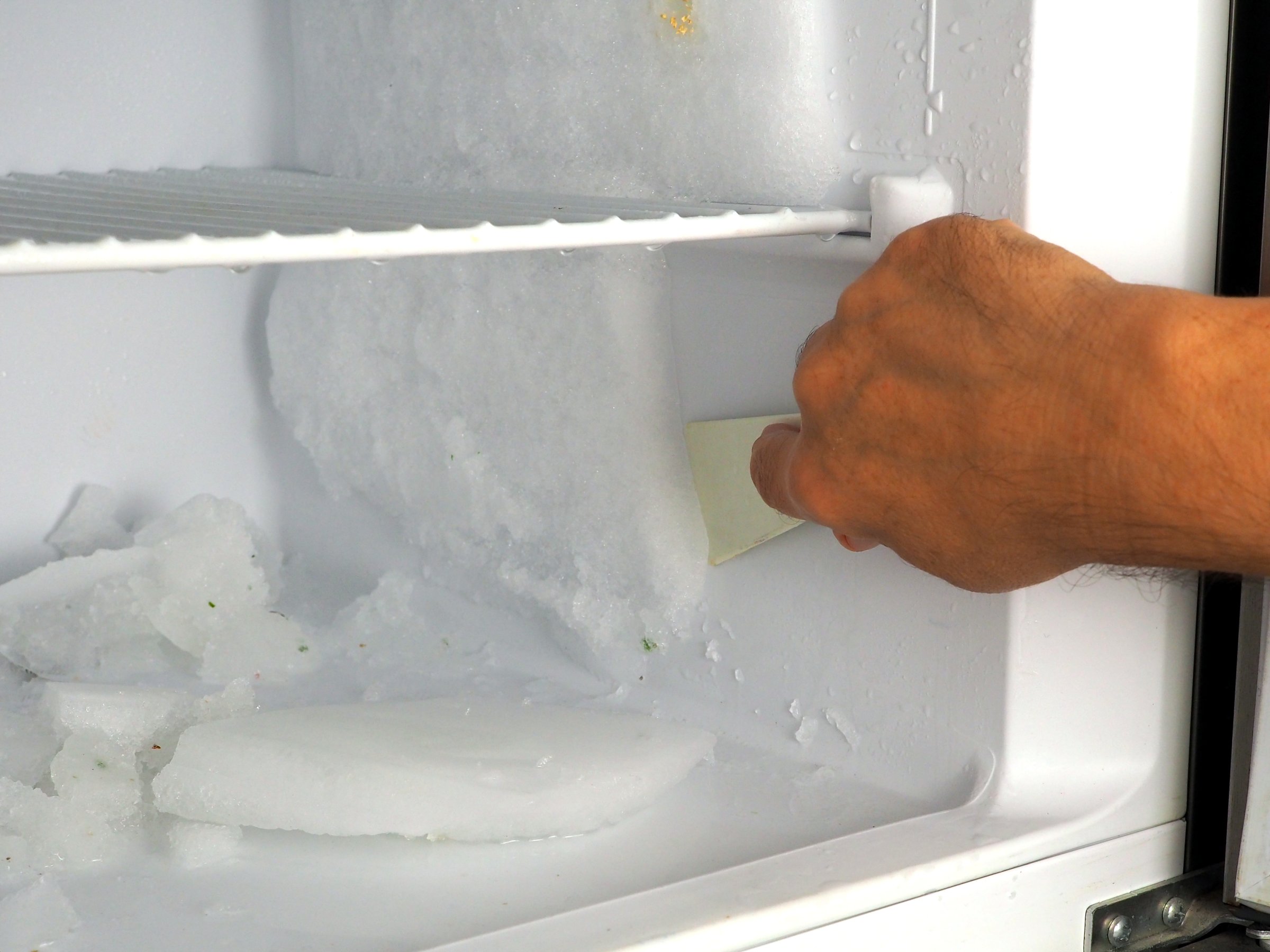 Manual Defrosting of Freezer Compartment with Ice Scraper and Melting Frost Removal