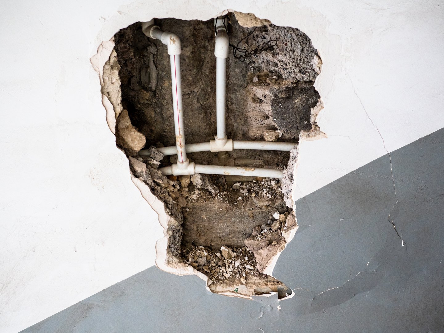 view of new plastic water pipes in broken wall of old apartment building