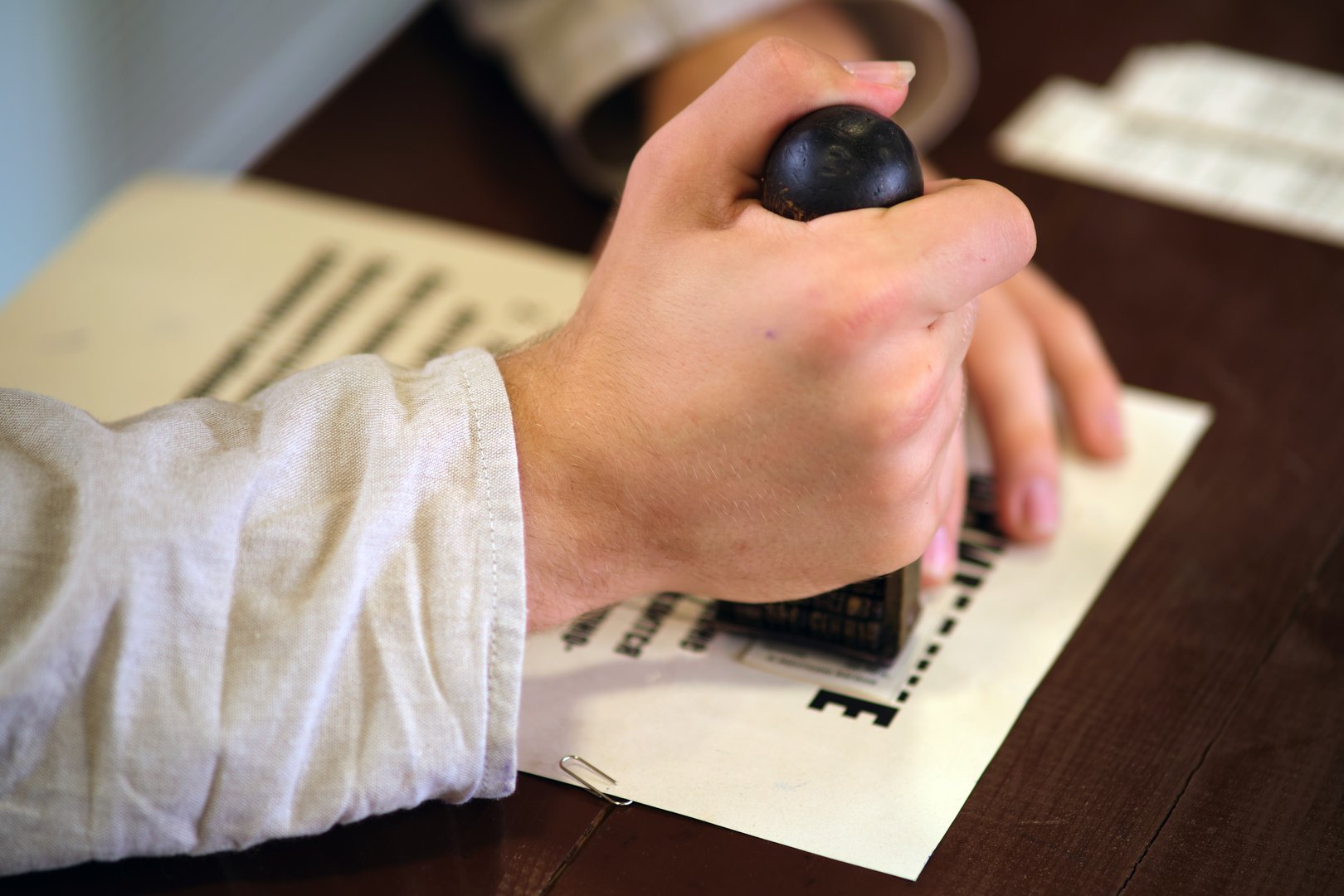 A man's hand puts a seal on a piece of paper, close-up