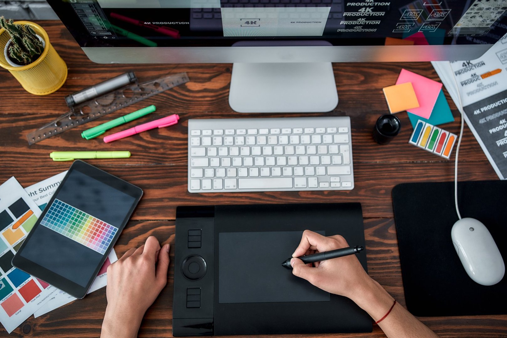 Top view of a designer using graphic tablet and working with computer while sitting at his workplace in the office. Top view of a workplace with graphic tablet, keyboard and computer.
