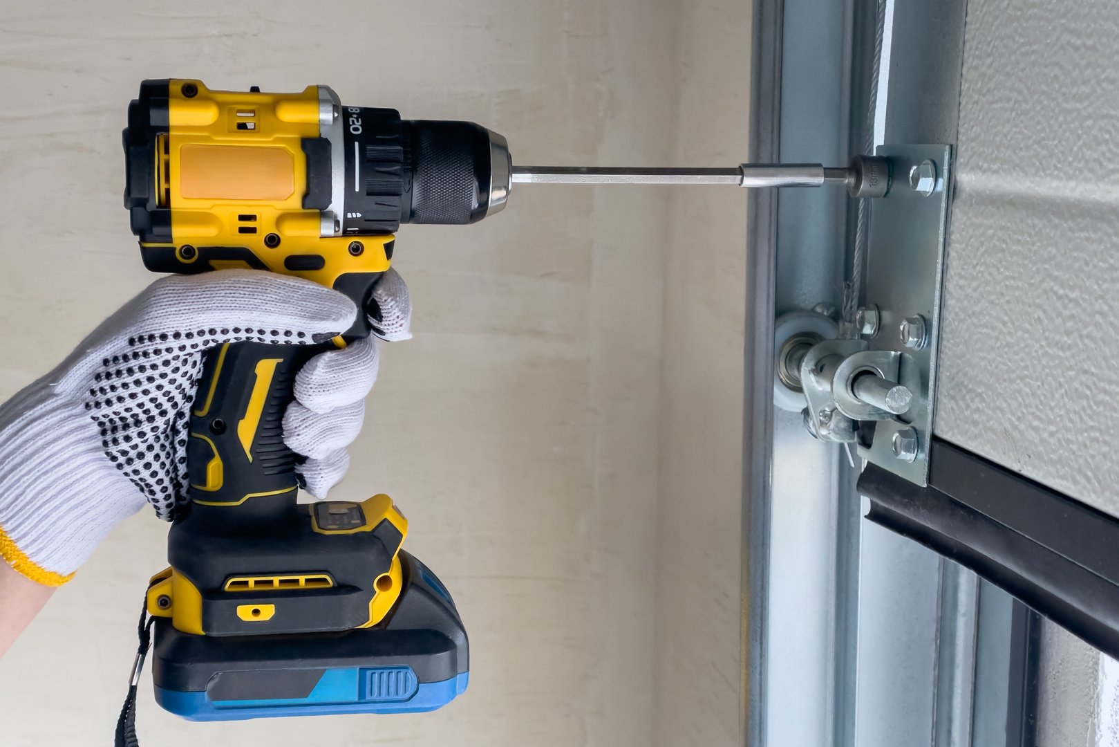 A craftsman assembles sectional doors using a screwdriver. The concept of sectional door installation.