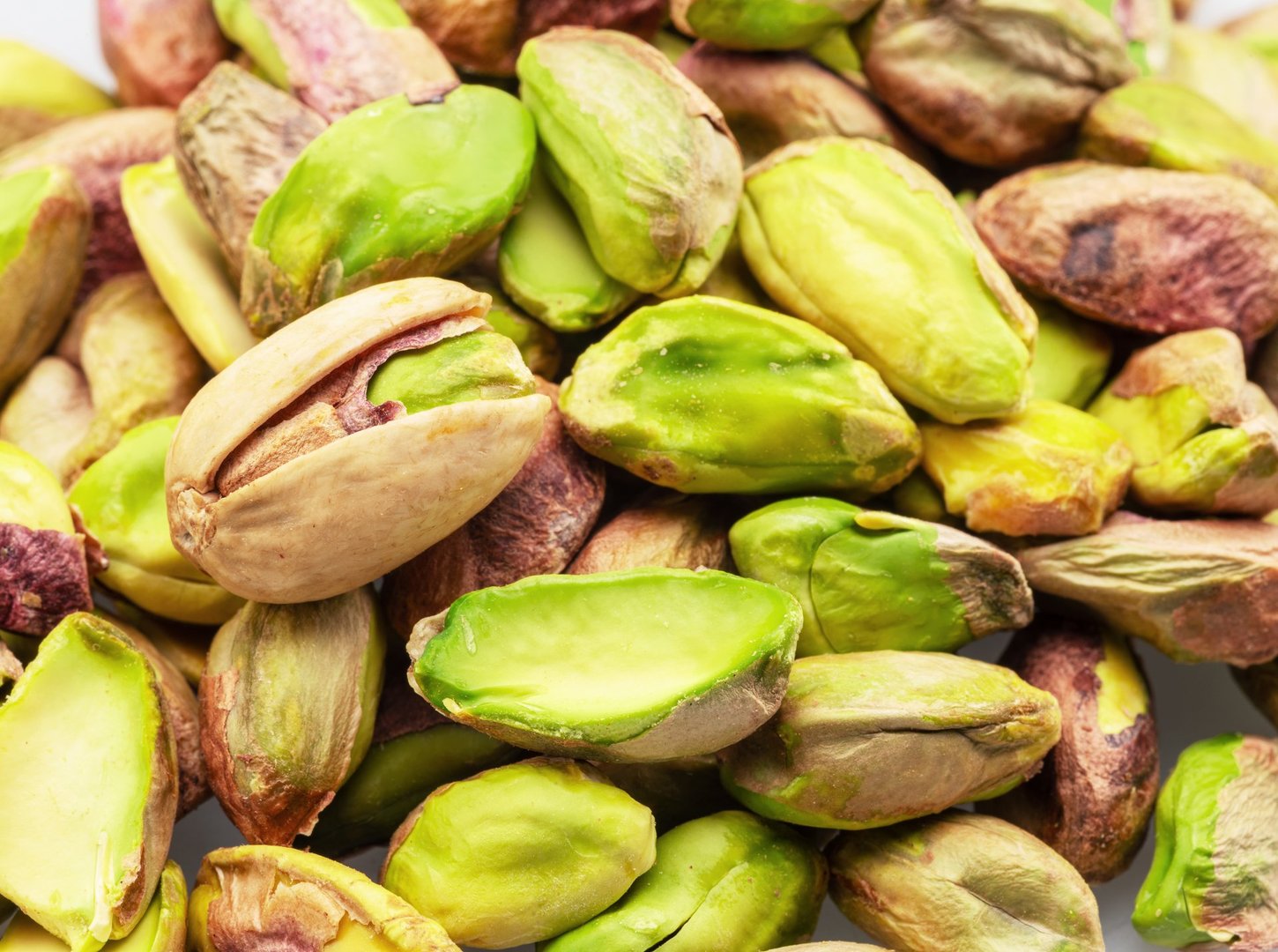 Group of raw peeled green pistachio nuts, macro shot.