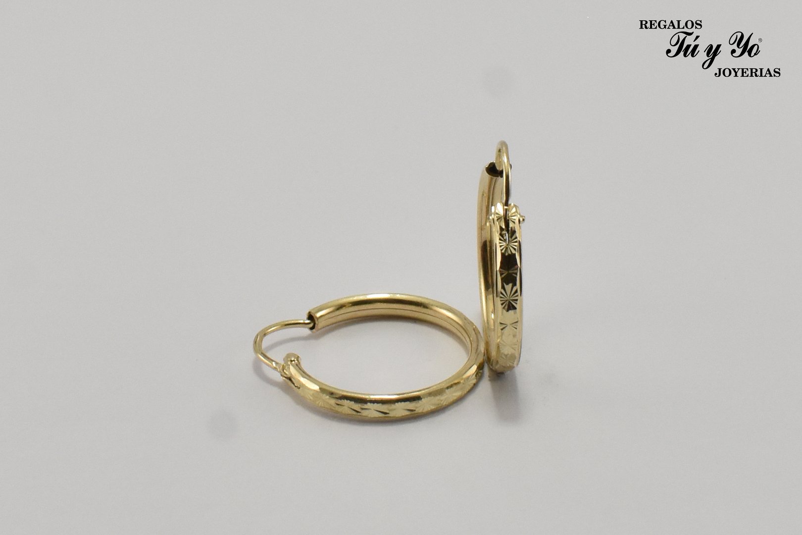 Pair of gold hoop earrings with engraved star pattern, displayed on a plain background.