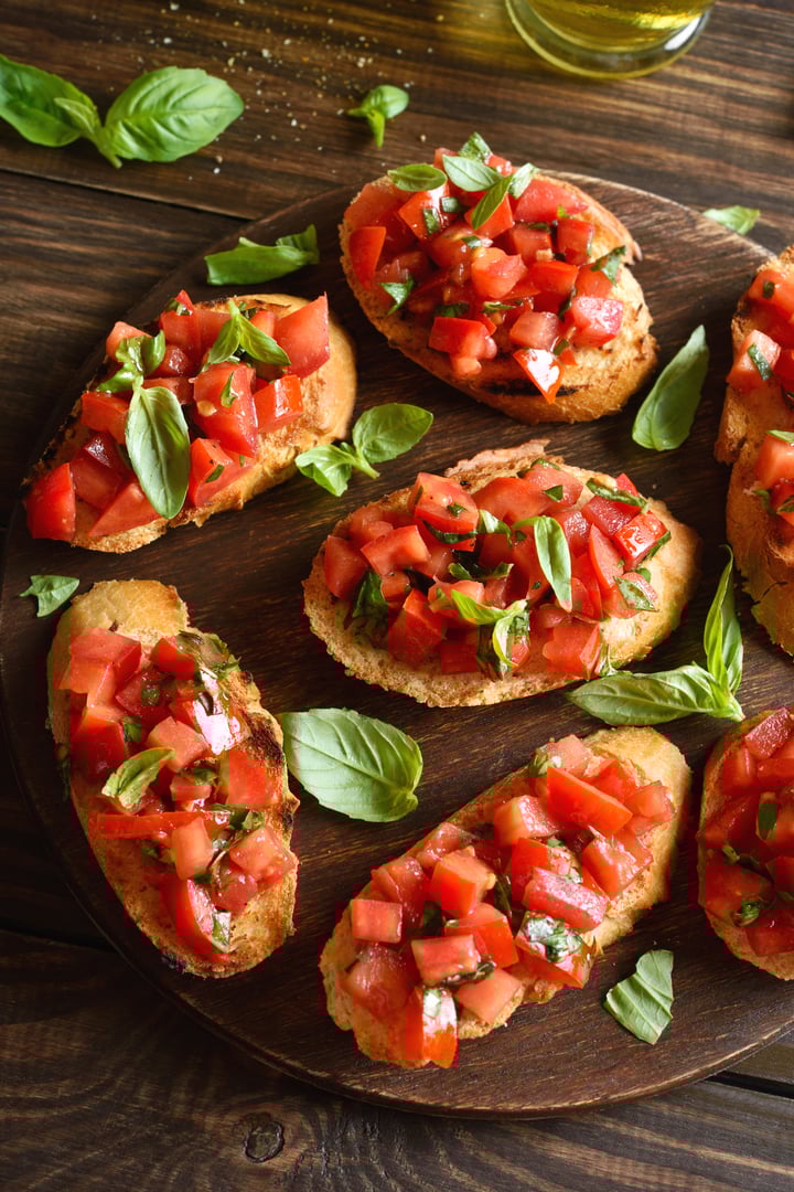Bruschetta with with cherry tomatoes and basil on brown wooden table. Close up view