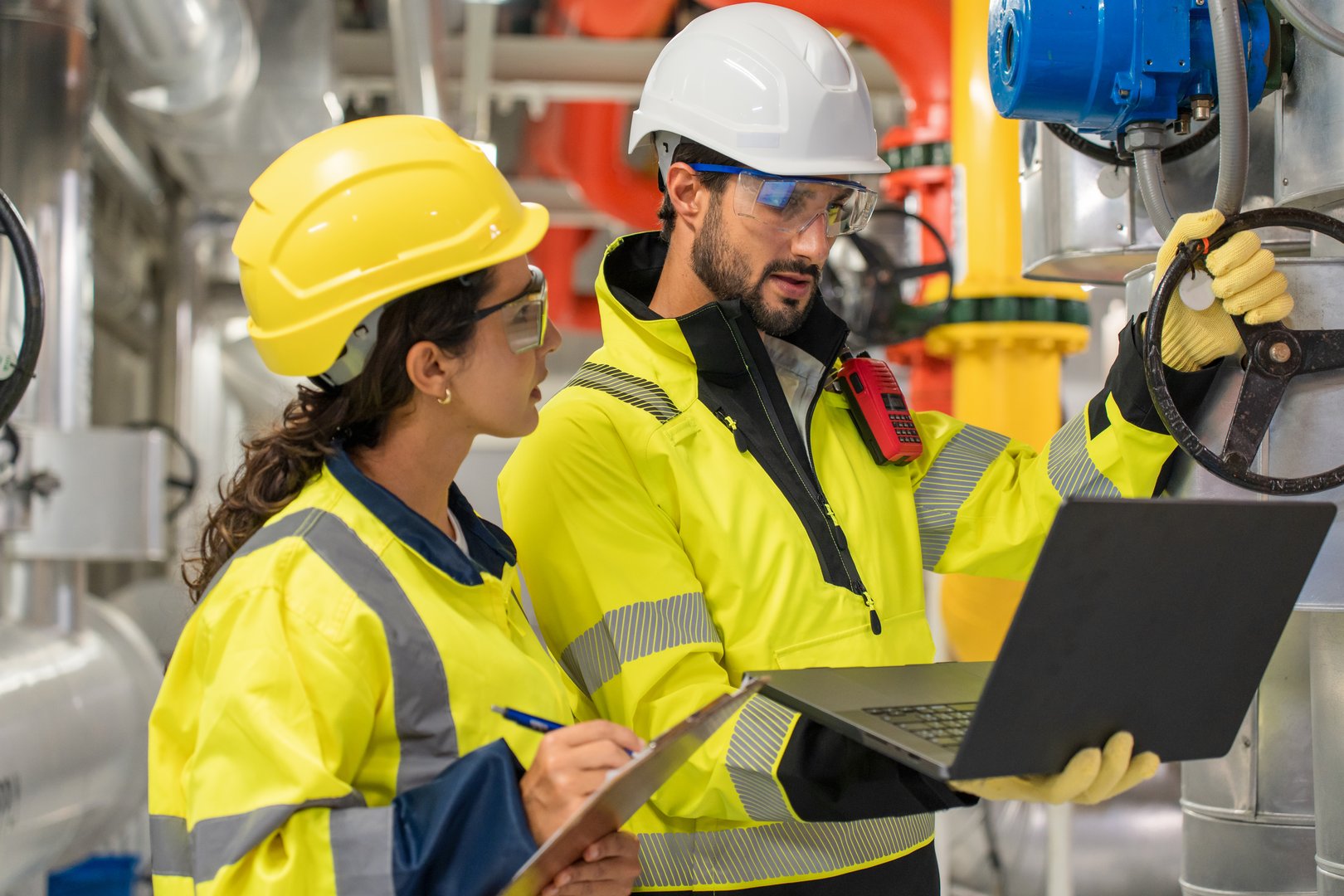 Two colleagues examining fan and refrigeration infrastructure for power efficiency in an industrial facility.