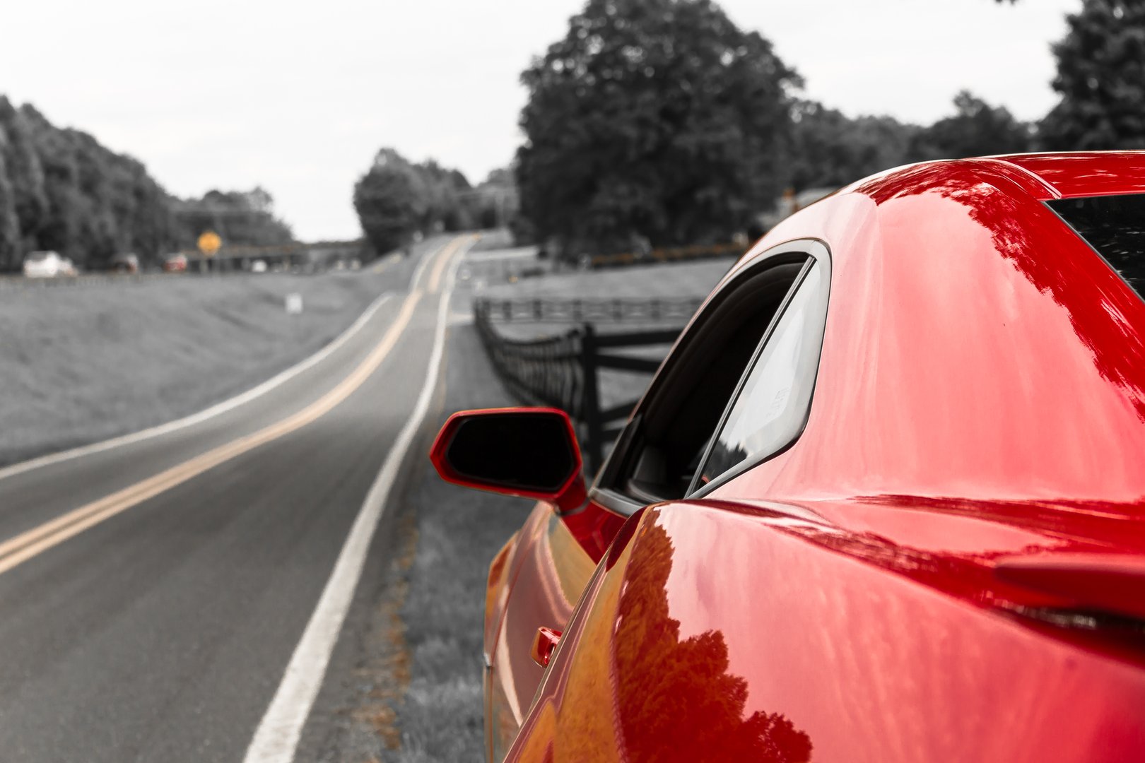 Red sports car on country road.