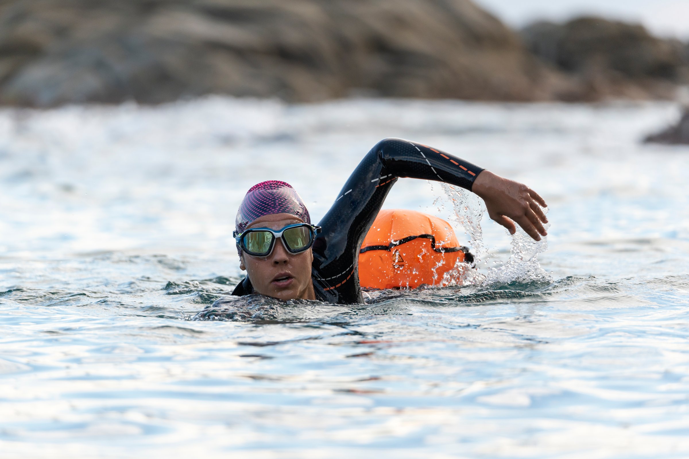 Portrait of a woman swimming in open water with wetsuit and buoy