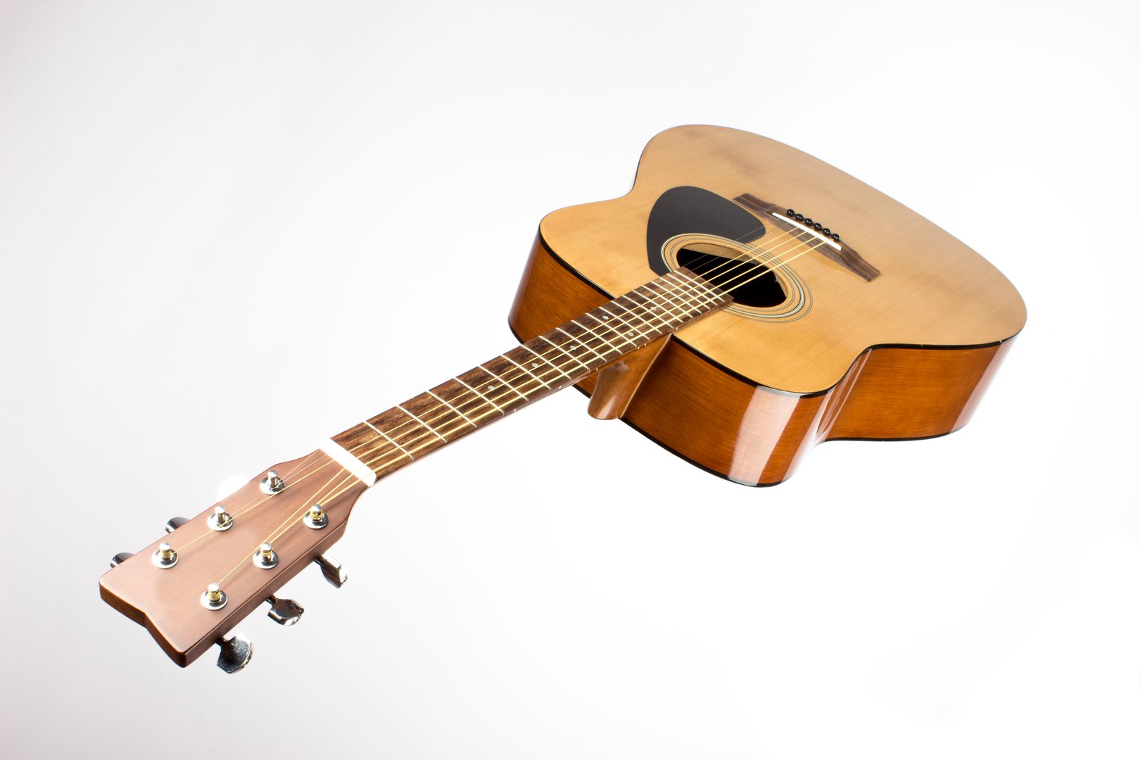 dreadnought six-string acoustic guitar made of light wood on a white background. an isolated object. close-up. with a place for the text. view from below