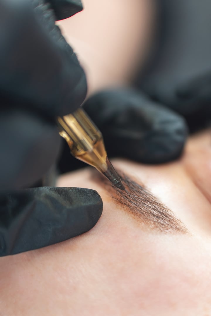 A cosmetologist does permanent tattooing of women's eyebrows.