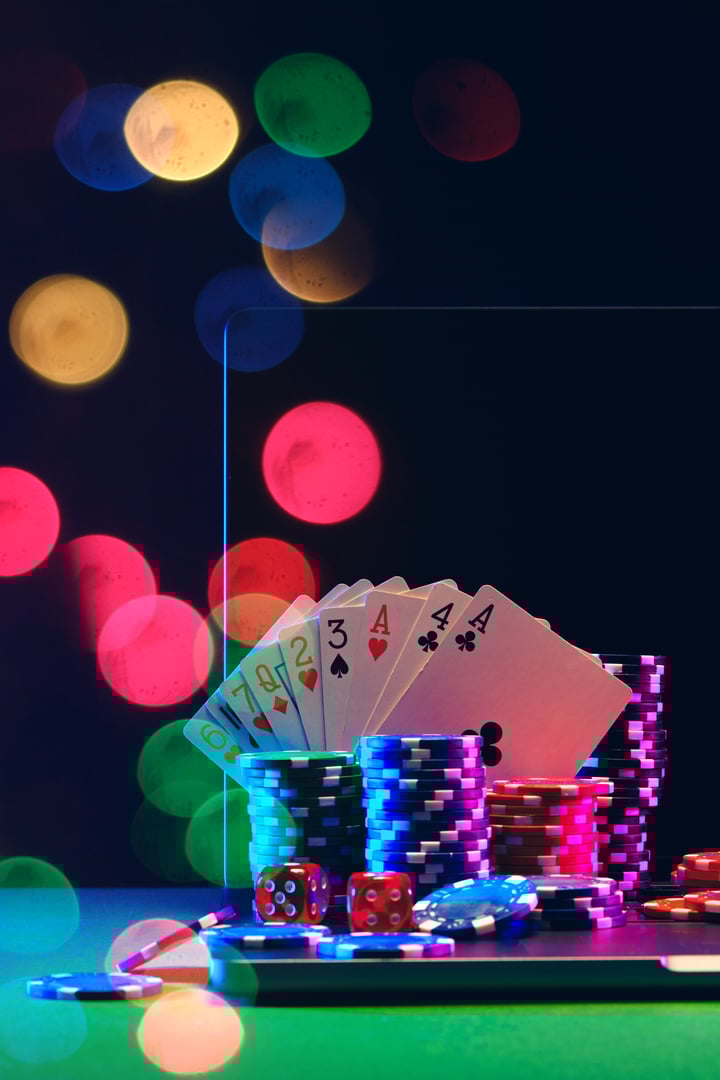 A laptop computer with a black screen sits on a green table, illuminated by colorful lights.