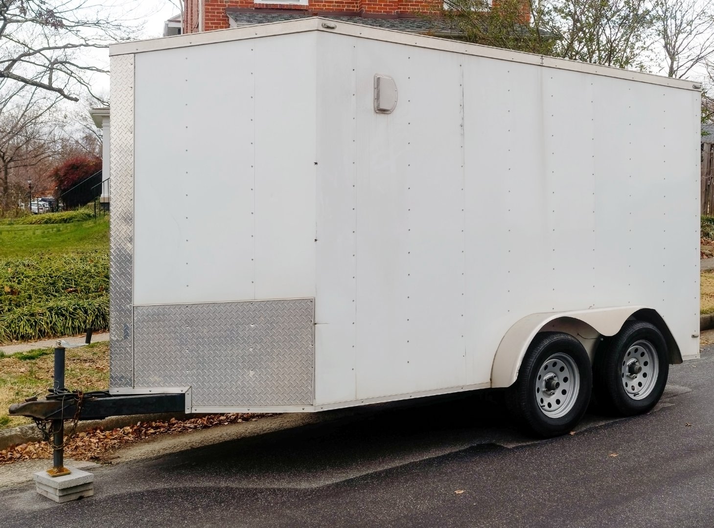 Front view of small white cargo trailer parked on neighborhood street.