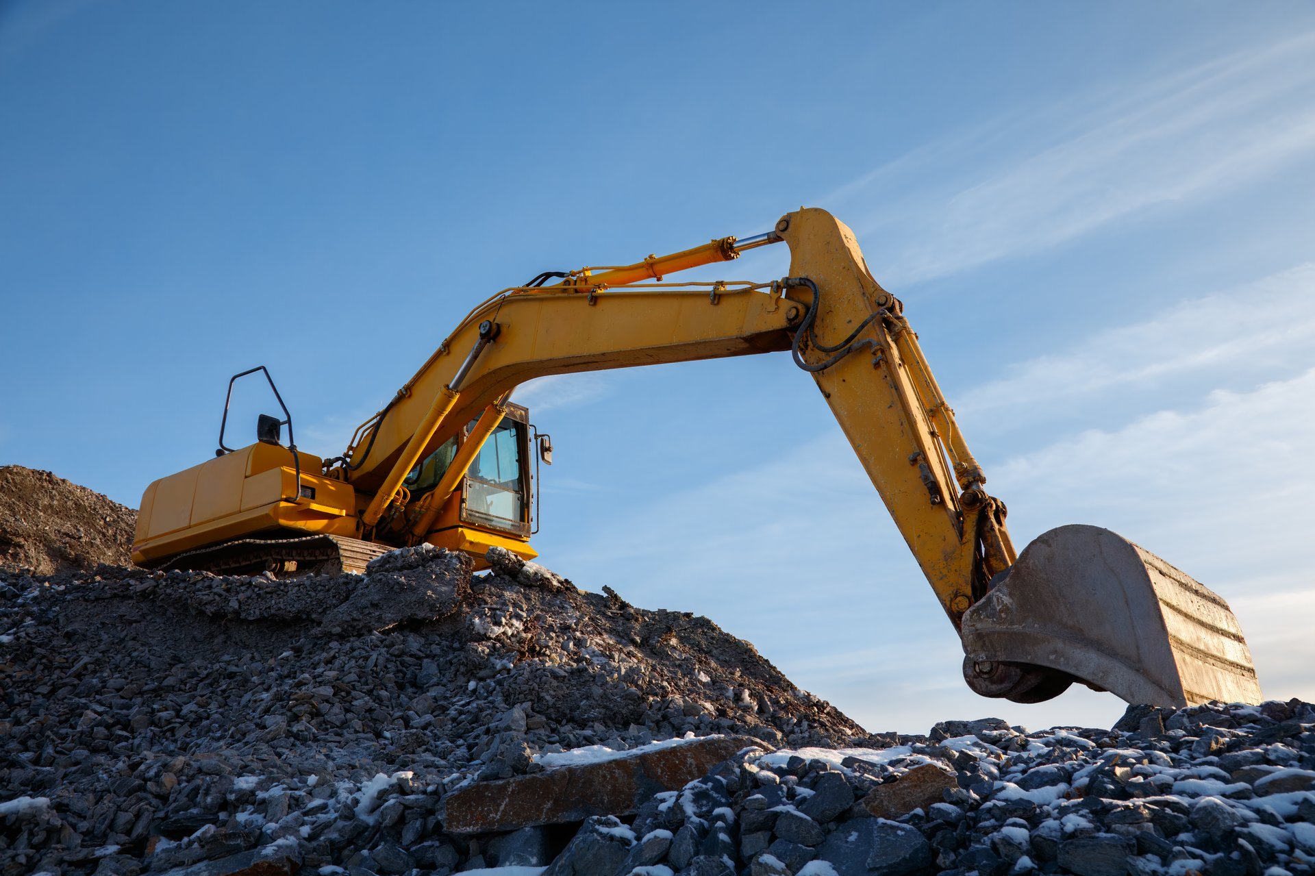A yellow excavator operating on a rocky construction site, earthmoving heavy machinery in infrastructure projects.