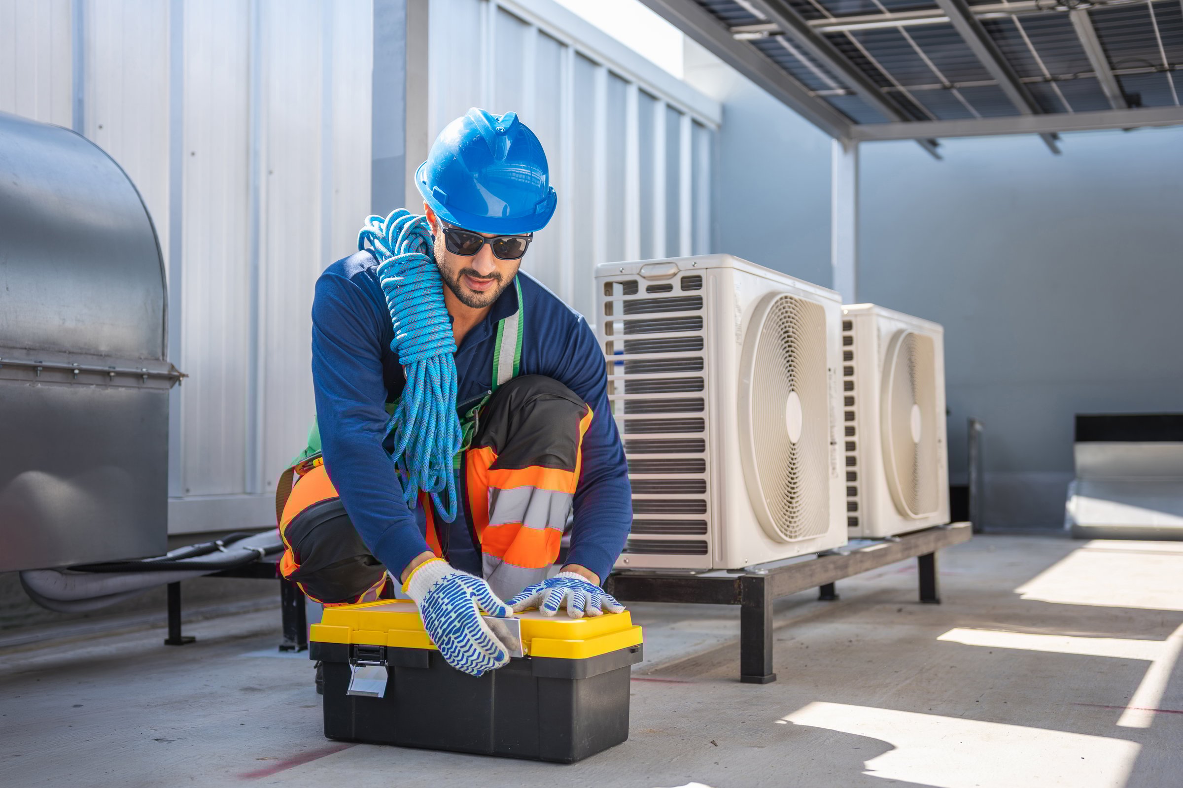 Professional HVAC technician opening toolbox to repair air conditioning units on rooftop