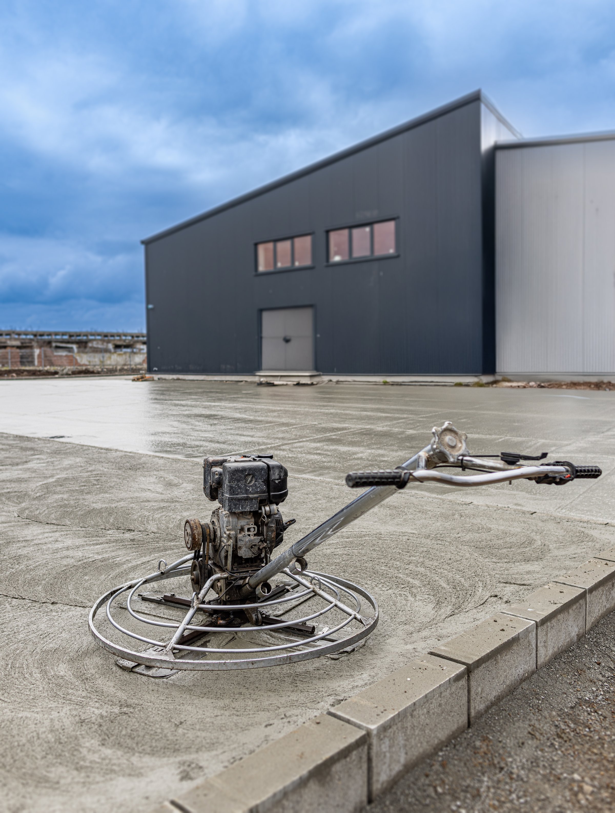 Concrete finishing process using a power trowel machine on a freshly poured concrete slab at industrial building construction site