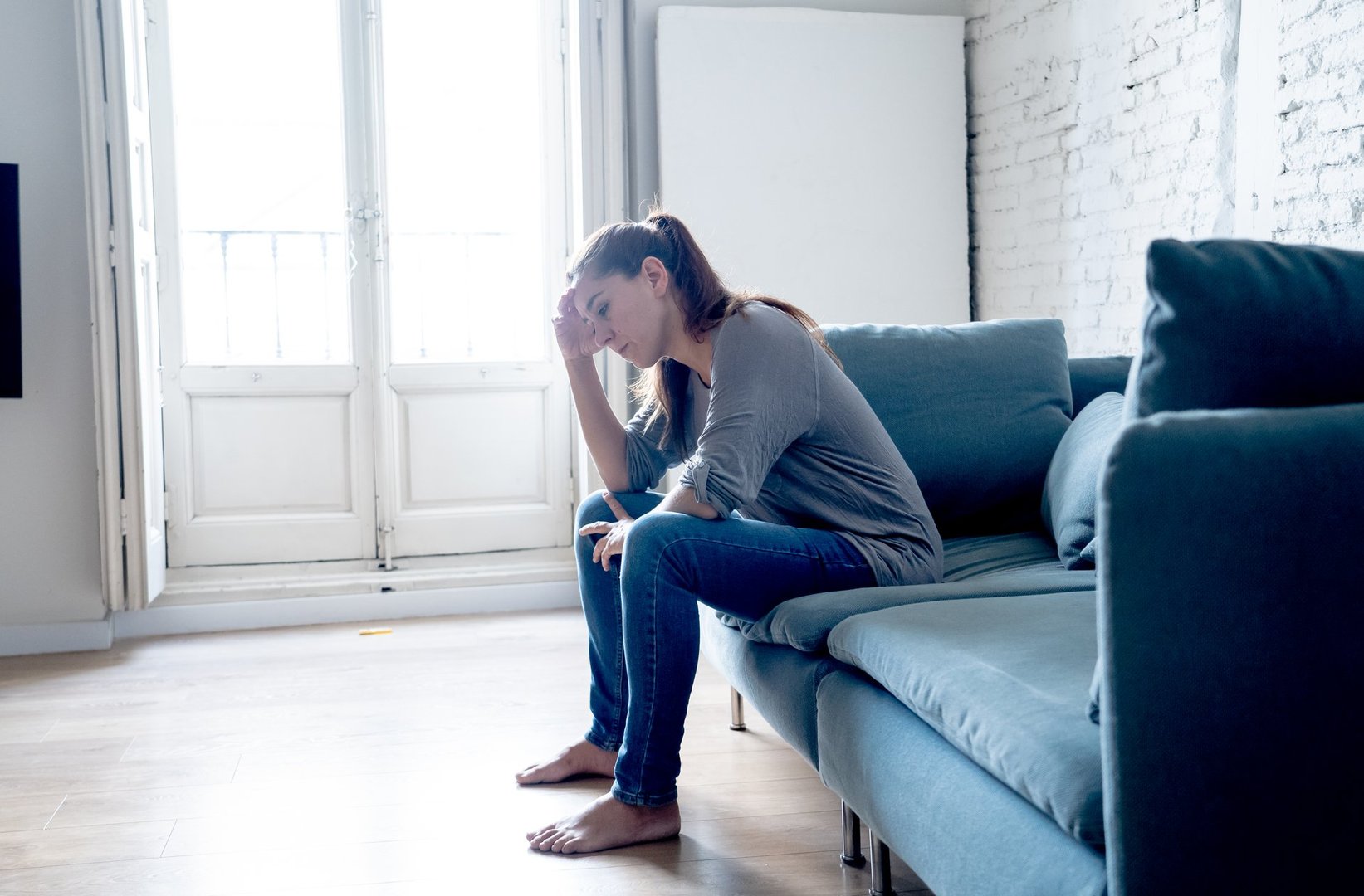 Young attractive latin woman lying at home living room couch feeling sad tired and worried suffering depression in mental health, problems and broken heart concept.