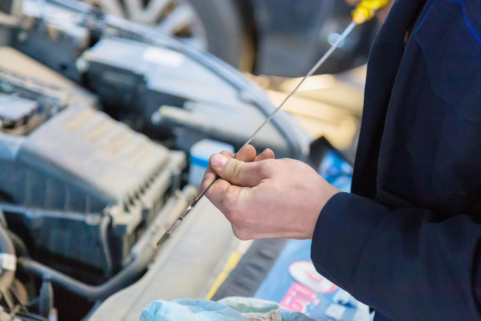 Car repair service. Mechanic checking the oil level with dipstick in car engine