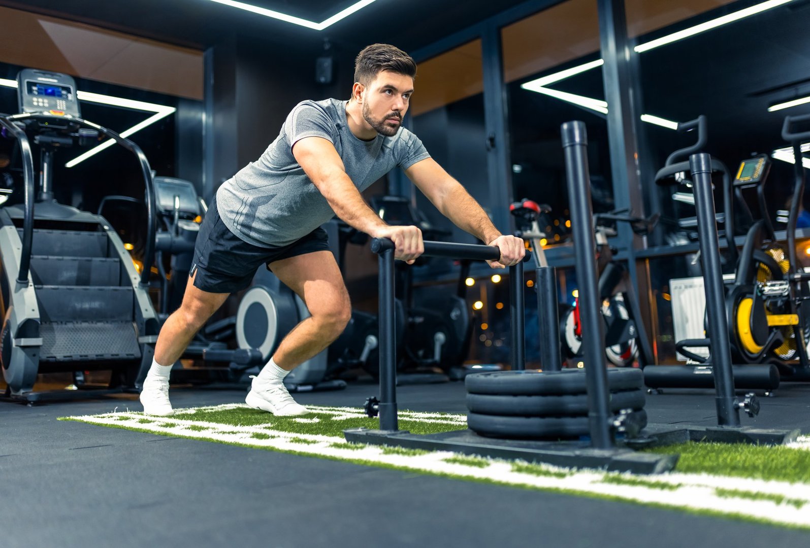 Muscular sporty man pulls weights across the floor of the gym.