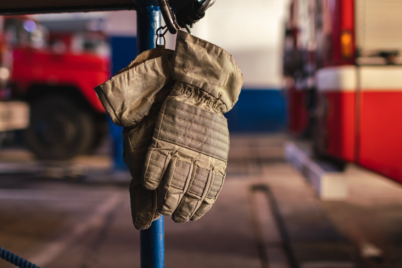 Firefighter gloves in a fire station with a fire truck in the background