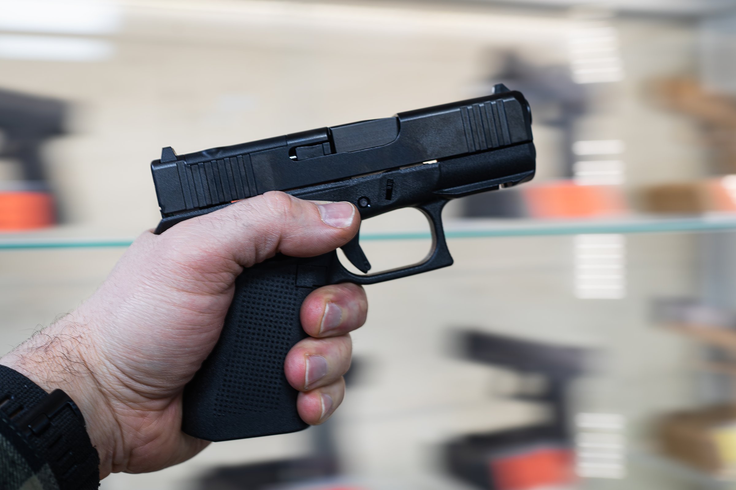 Modern compact 9mm pistol in a man's hand in a gun shop, soft focus photo as an artistic element.Close up photo