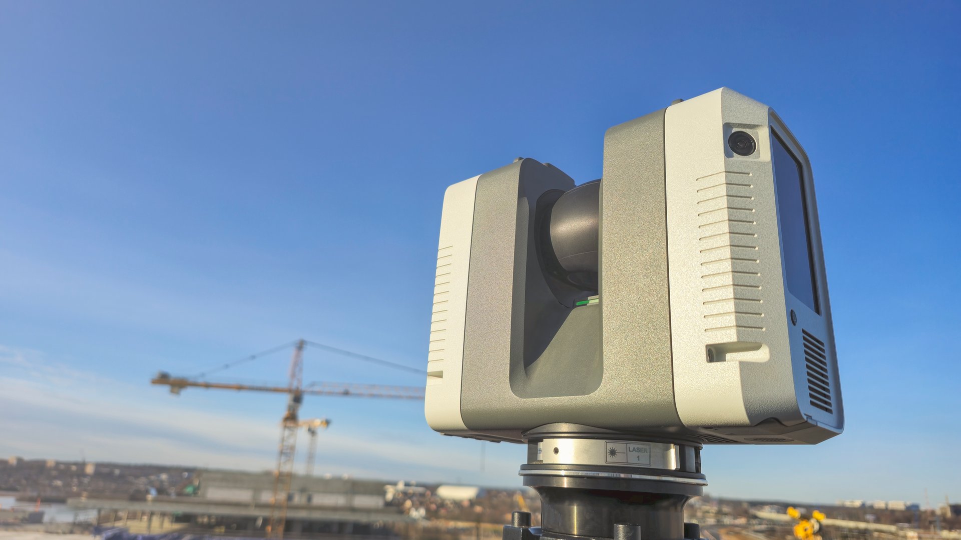 Geodesic 3D scanner against background of blue sky and construction crane. Implementation of geodetic accurate measurements during construction.