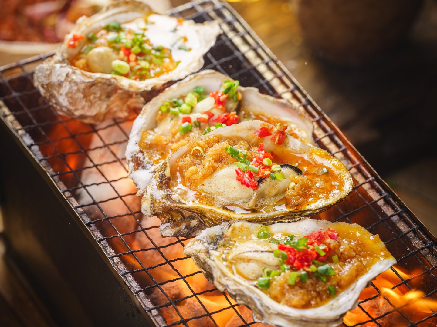Grilled oysters with garlic chili soy sauce and other seasonings, close-up