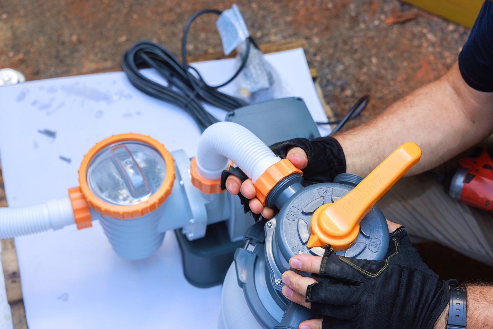 Contractor attaches components of swimming pool pump system on outdoors near swimming pool