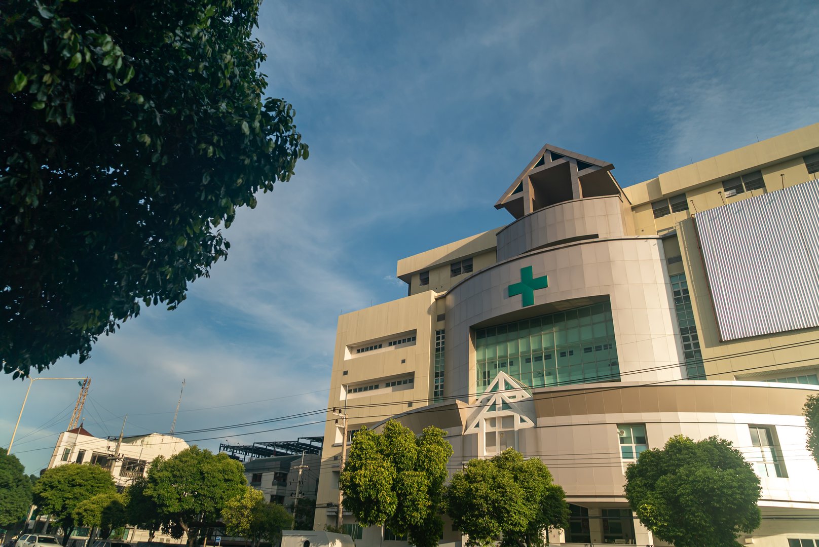 A modern pharmacy building showcases contemporary architecture under a clear blue sky. Green signage stands out against the facade, enhancing accessibility and visibility.