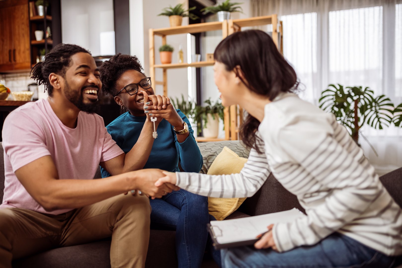 Multiracial couple buying a flat, house from Asian real estate agent. Shaking hands to make a deal.