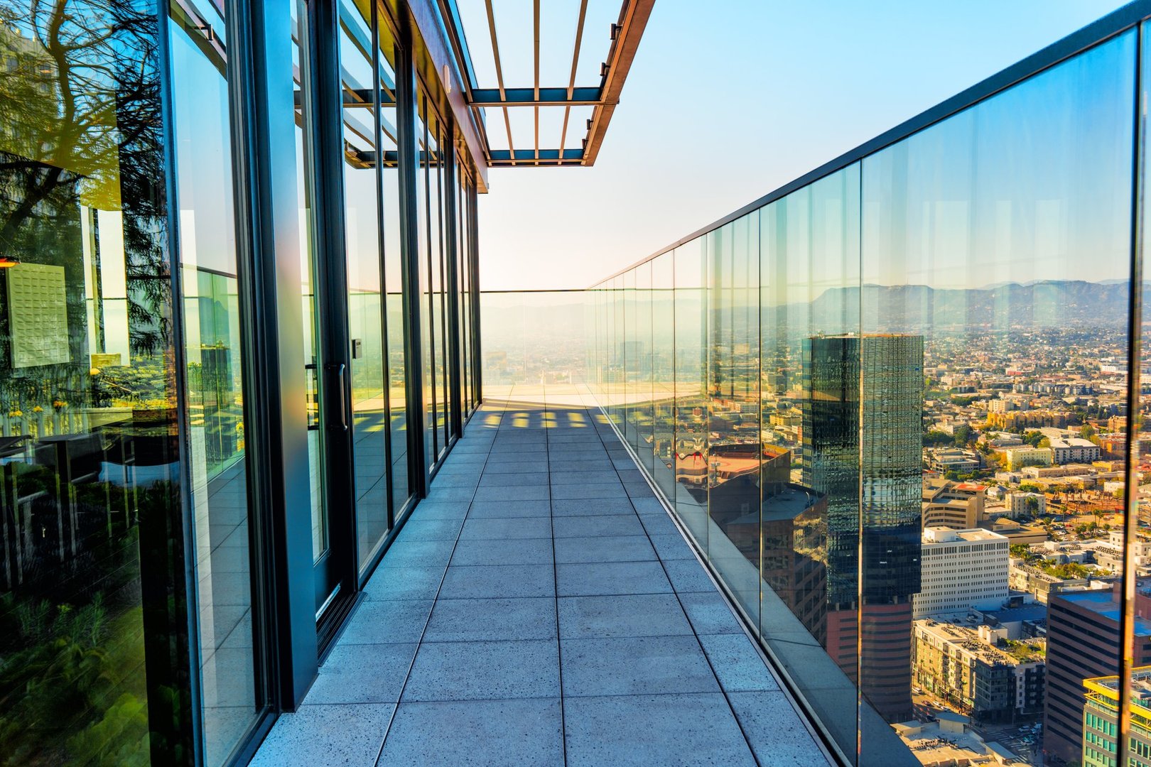 Luxury balcony of the residential complex in the LA center with a glass facade and stunning view of the city.