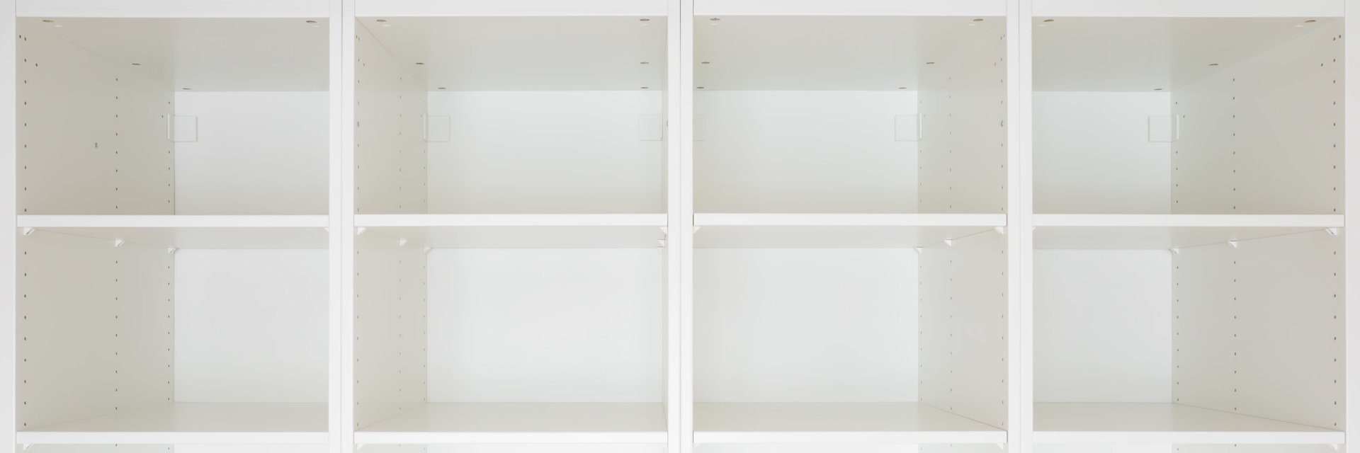 Opened new white wooden wardrobe with empty shelves for books, clothes, shoes or different things, goods and other products. Closeup. Wide banner. Front view.