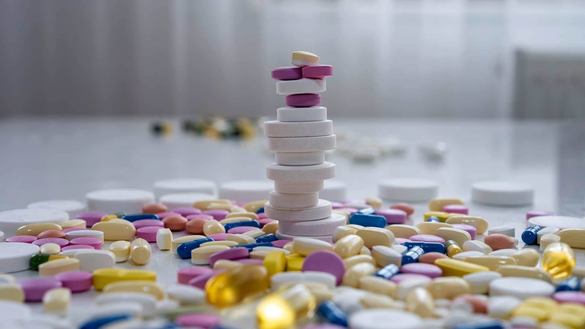 Medicine tablets and capsules in orange, red, yellow, white, blue, and green. Omega-3 tablets, vitamin pills