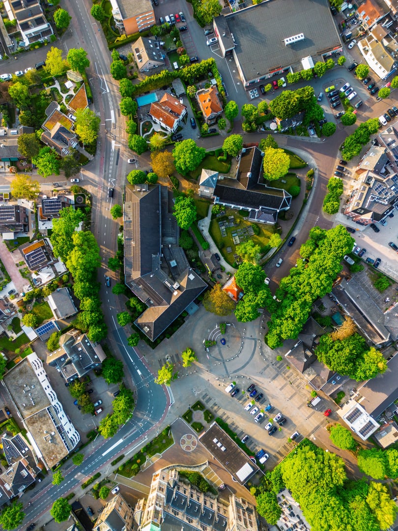 Aerial view of a European town with curving streets, compact buildings, green spaces, and a central plaza, blending historic charm with organized urban design.