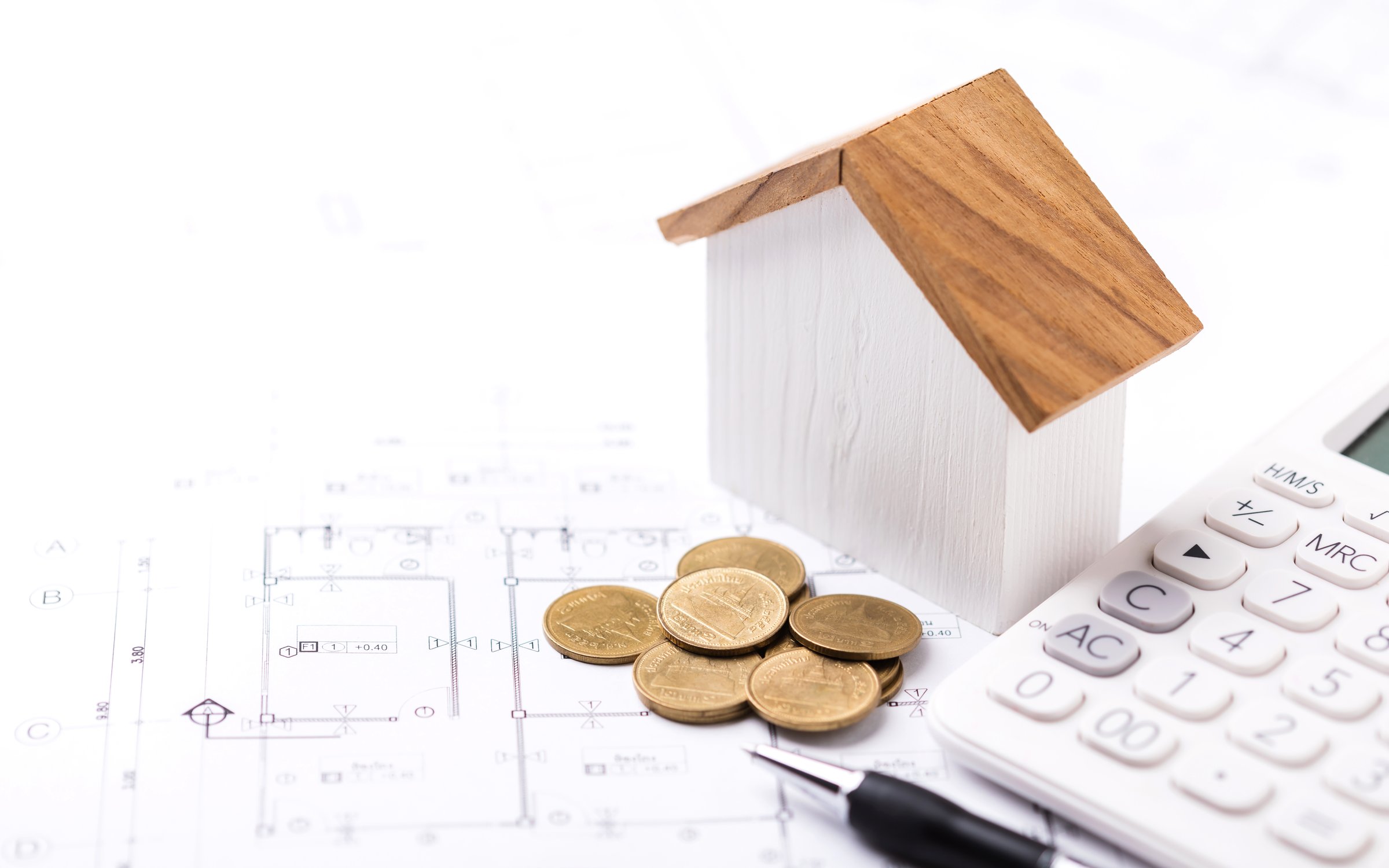 A concept of budgeting for home construction, with a house model, calculator, and construction plans placed on a table, symbolizing financial planning for building a home