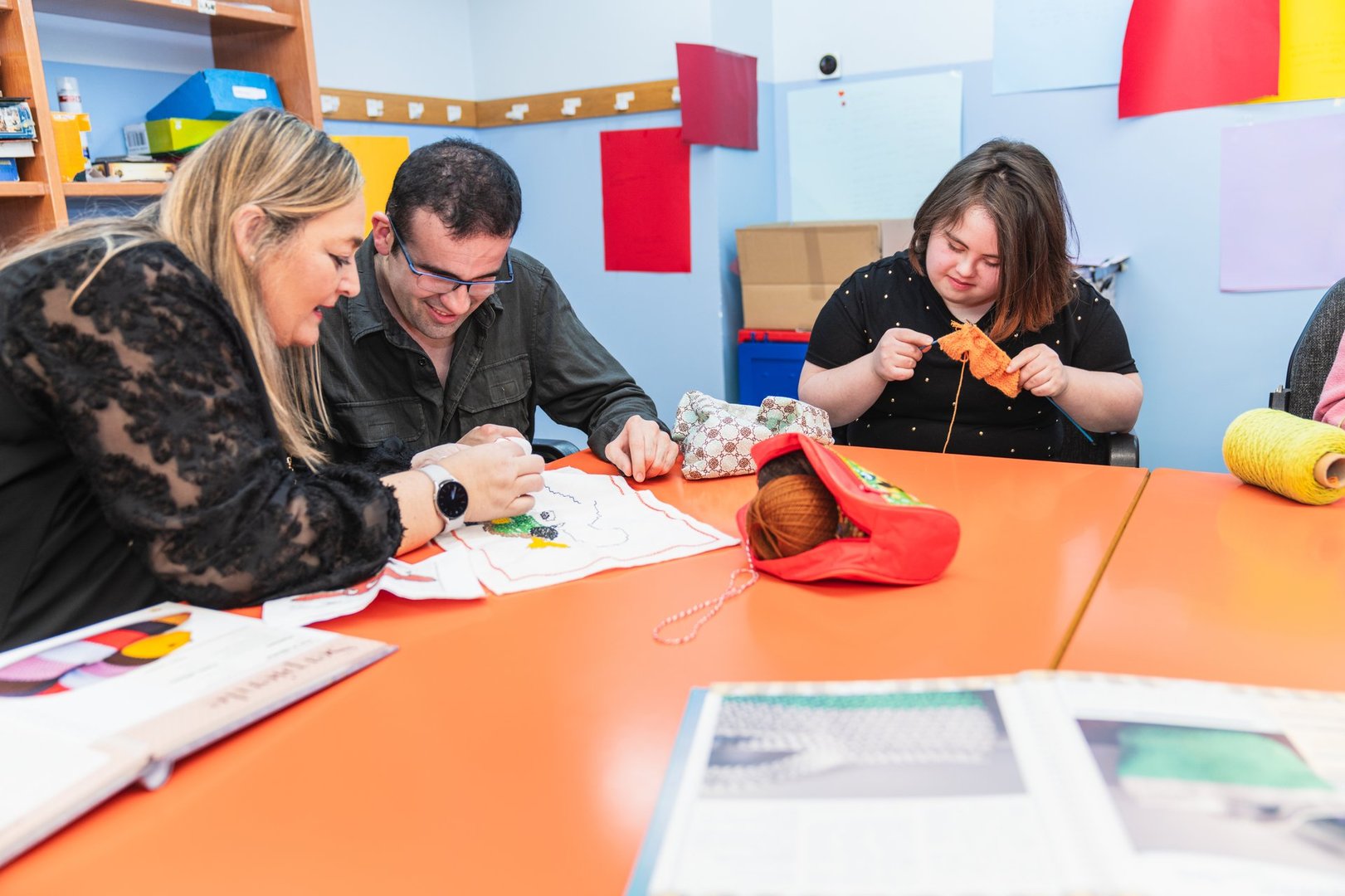 Instructor teaches sewing to adults with mental disabilities, one with Down Syndrome.