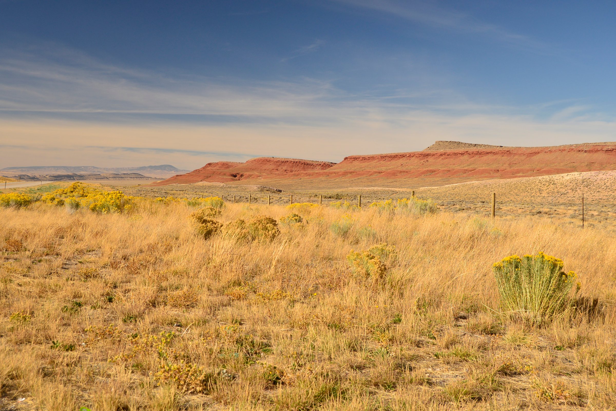 A stunning semi-arid landscape featuring a red rock plateau stretching across the horizon