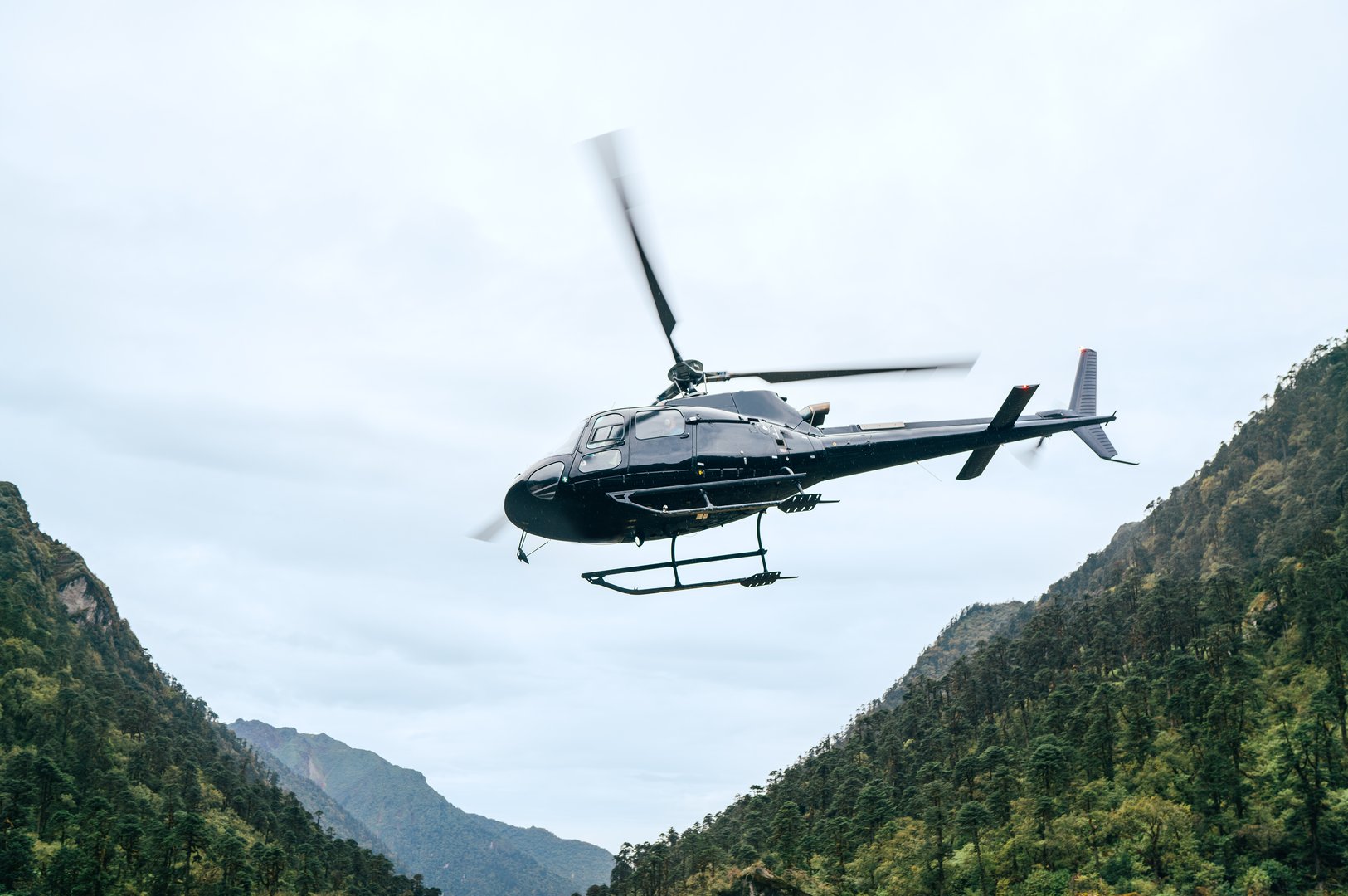 Civil helicopter flying UP in high altitude Himalayas mountains near Kothe settlement, Nepal. Mera Peak climbing  trekking route. Safety air transportation and travel insurance concept image.