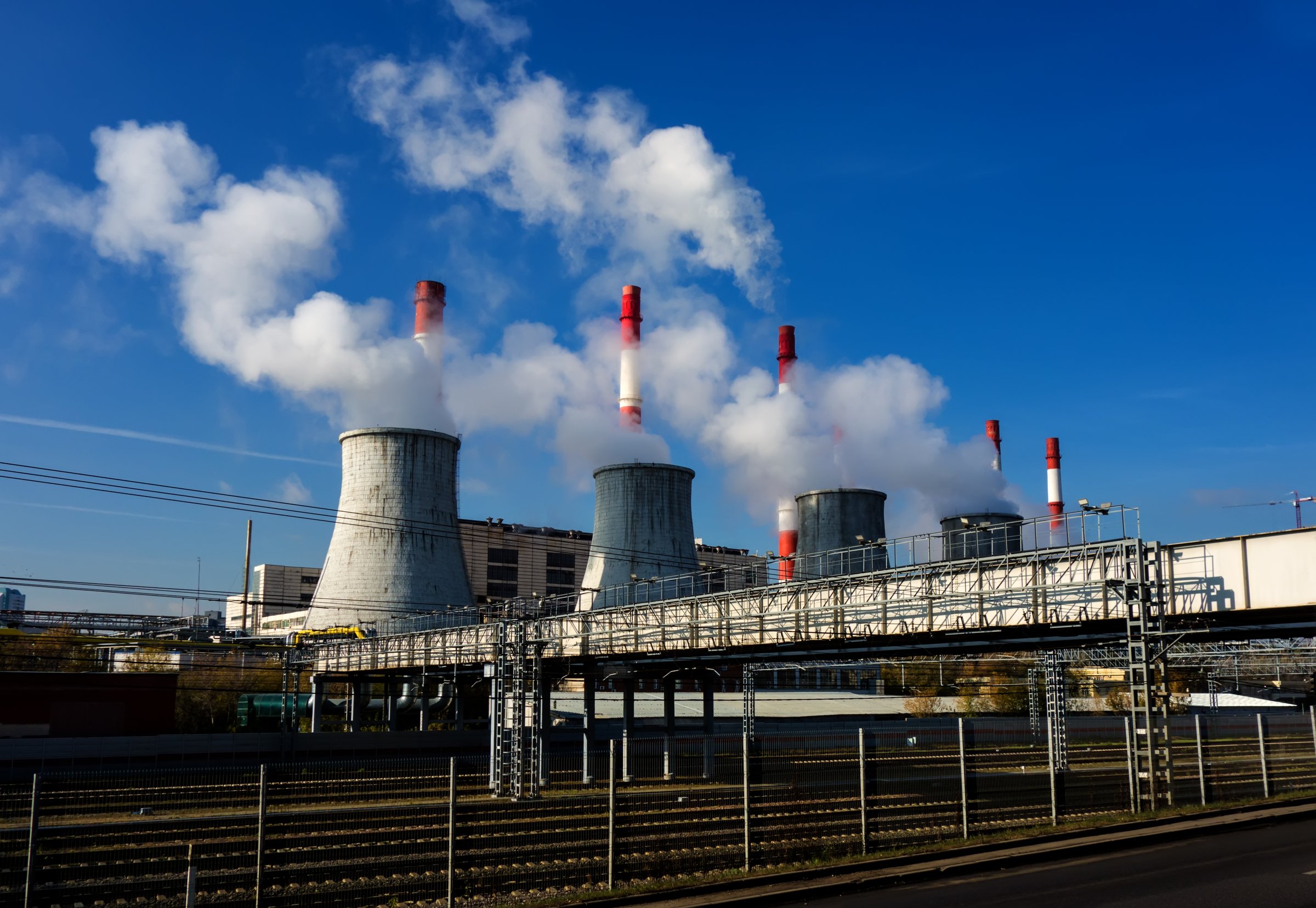Pipes with smoke. Smoking pipes of power plants against the blue sky. Puffs of steam over cooling towers.