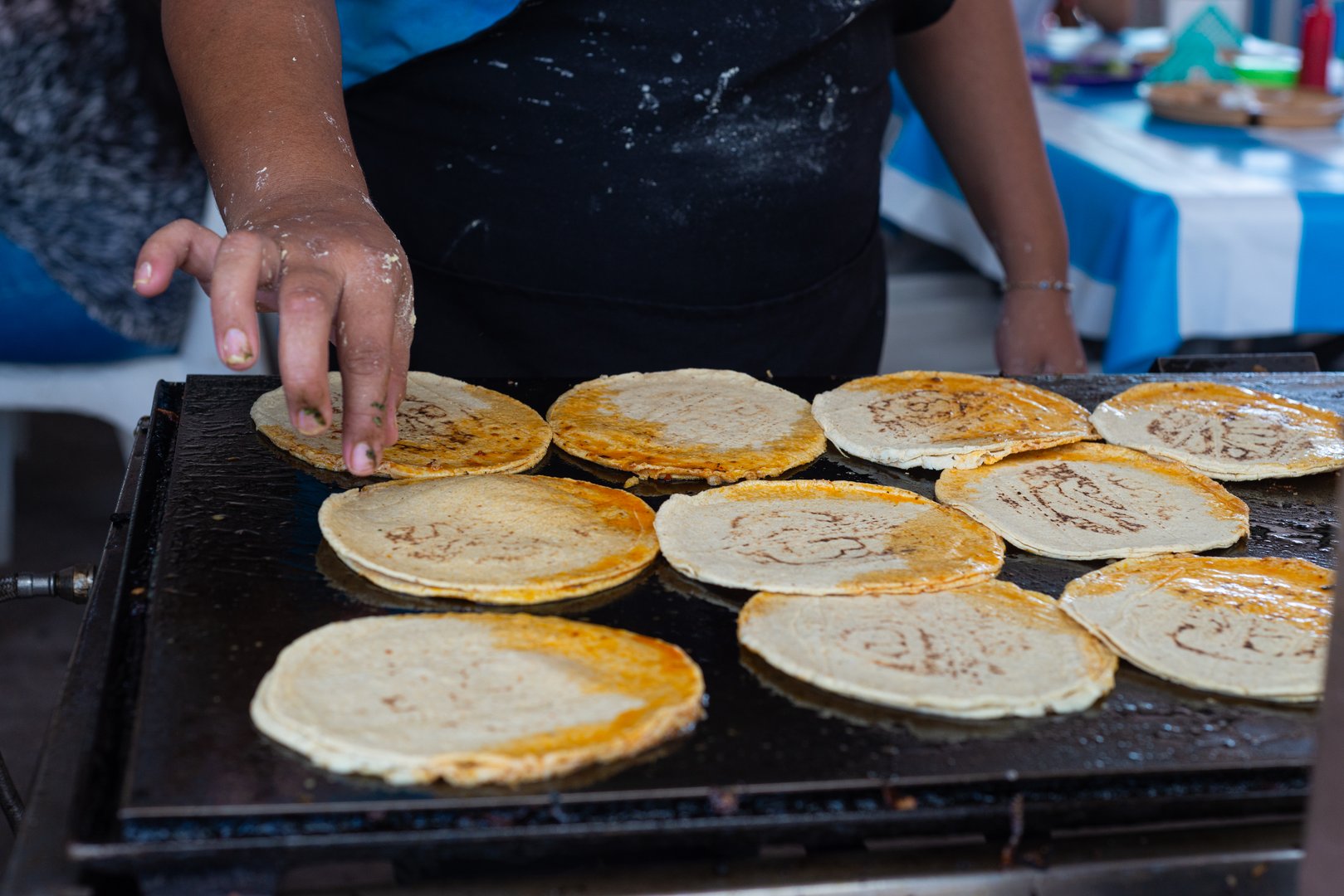 Female hands preparing tortillas on a hotplate. Street food stall in Mexico.
