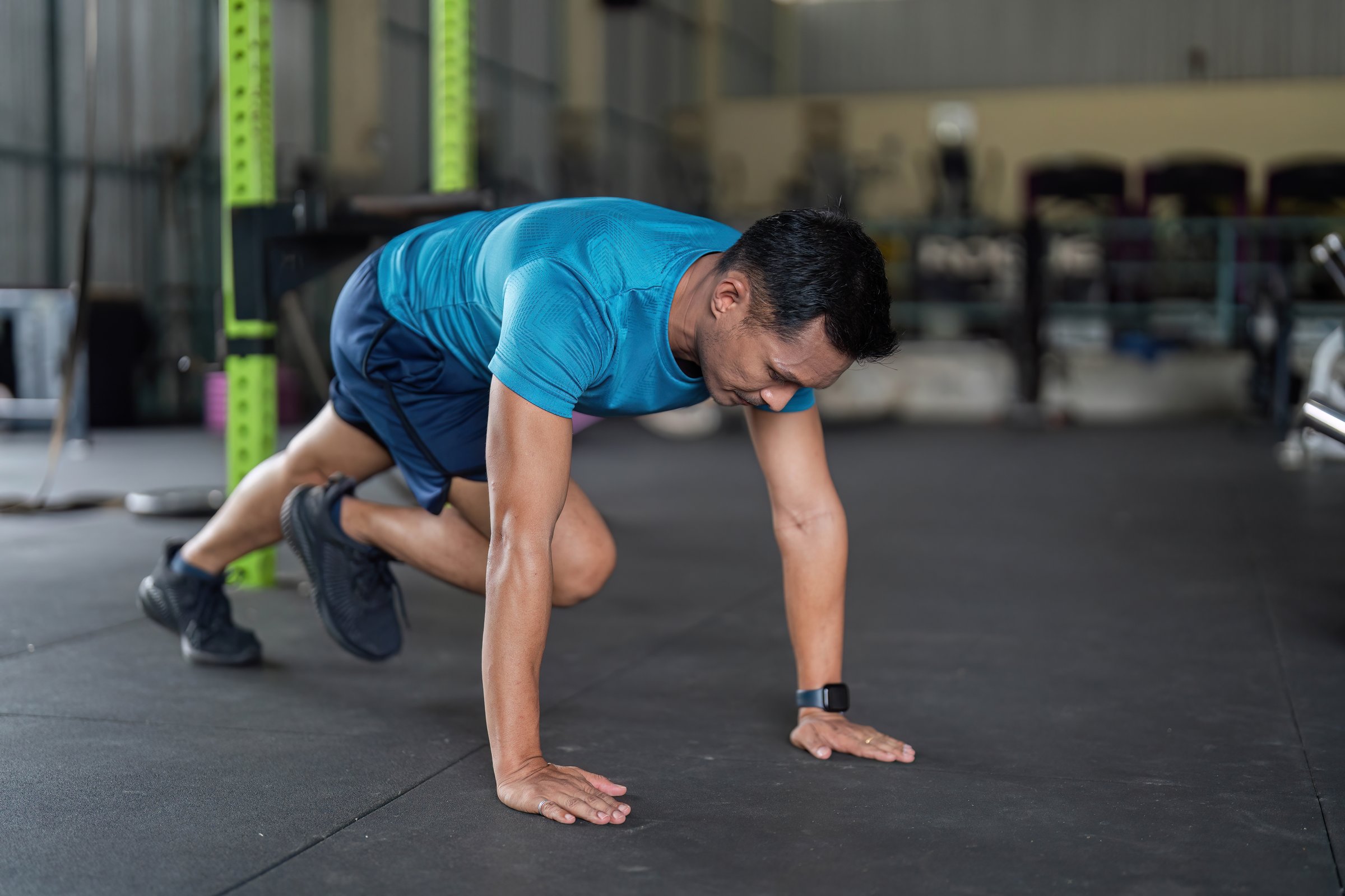 A man executes mountain climbers, showcasing agility and strength in a vibrant gym atmosphere.